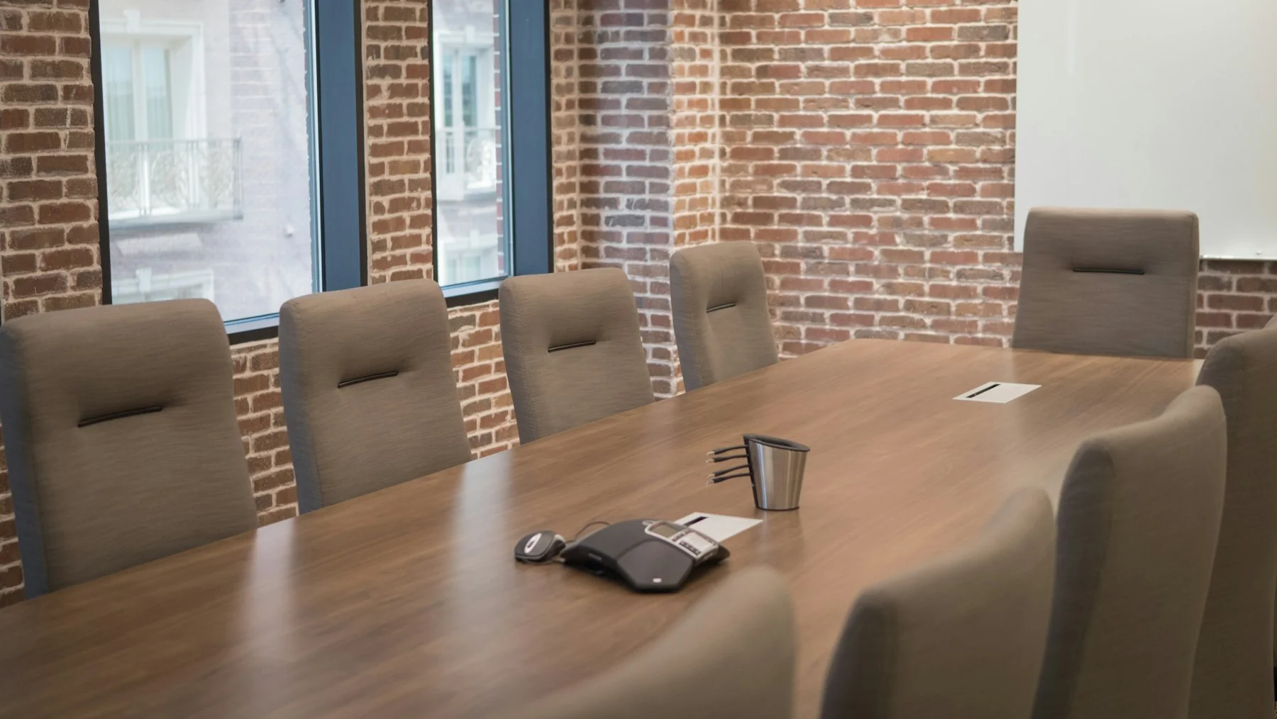 Sunlit meeting room with a wooden table and grey chairs